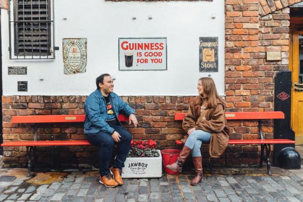 Students Lana and Miguel sit on red benches in Cathedral Quarter
