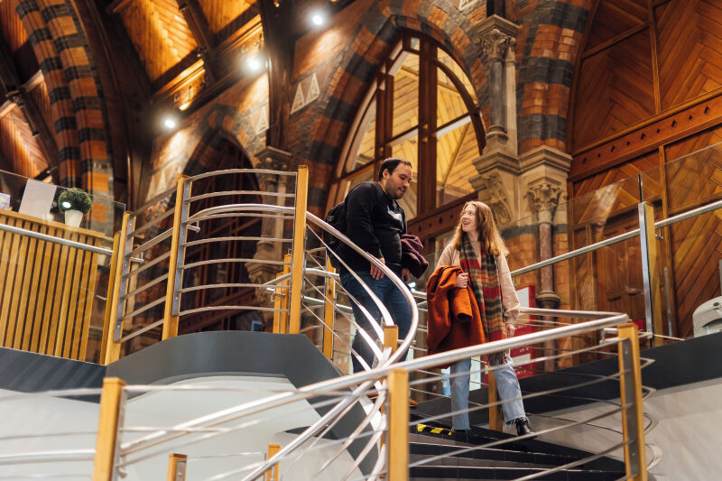 Students Lana and Miguel walking down steps inside the Graduate School