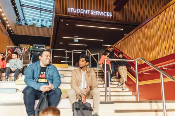 Students sitting and walking on stairs in One Elmwood
