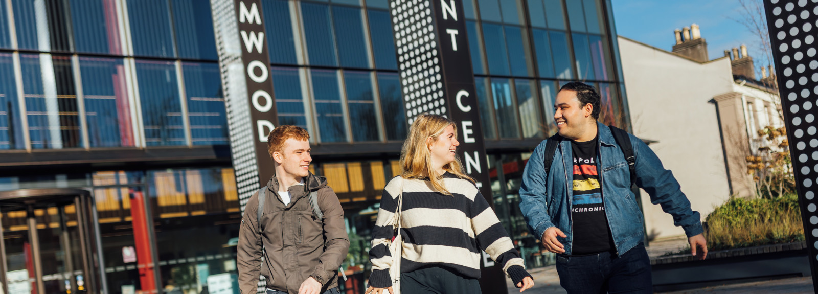 Three students walking outside the front of the One Elmwood building
